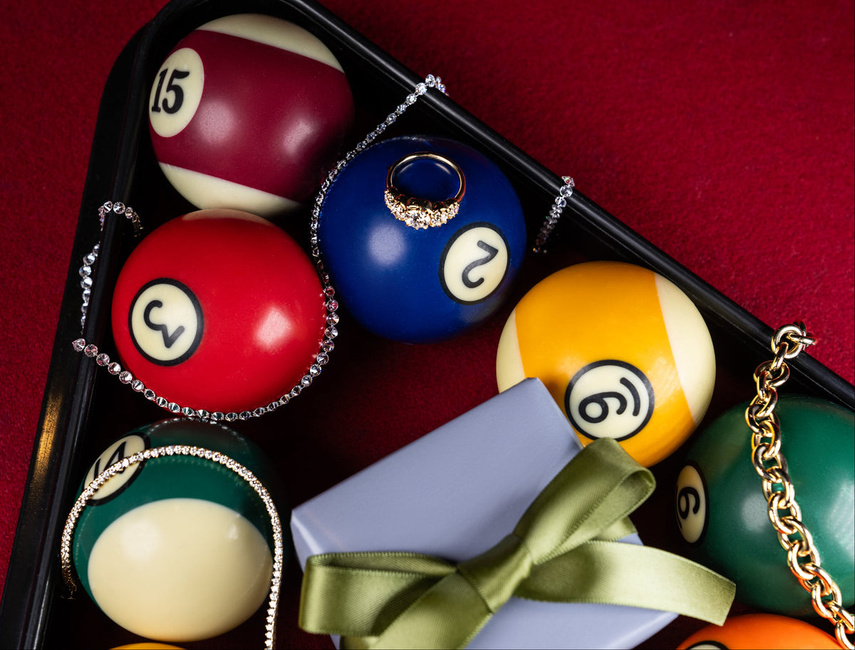 A pool triangle is filled with cue balls, and lab grown diamond and solid 14k gold jewelry and gift boxes to promote sophie ratner's holiday gift guide. shop now.