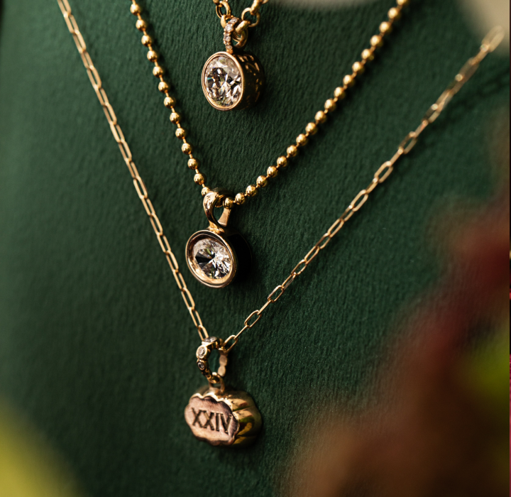 personalized neckalces with enamel, diamonds, birthstones or engraving showcased on a green velvet jewelry stand. Shop Sophie Ratner's fine jewelry holiday gift guide. Get a free diamond gift with orders $1,000+