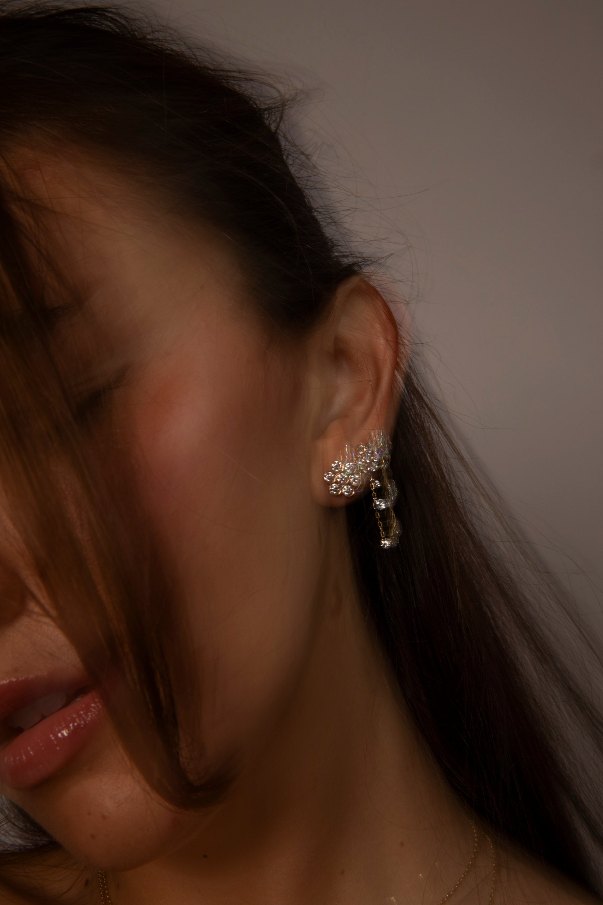 an intentionally blurred image showing a model wearing the new diamond flower stud from the afterglow collection. shop our lastest arrivals for summer 2026.