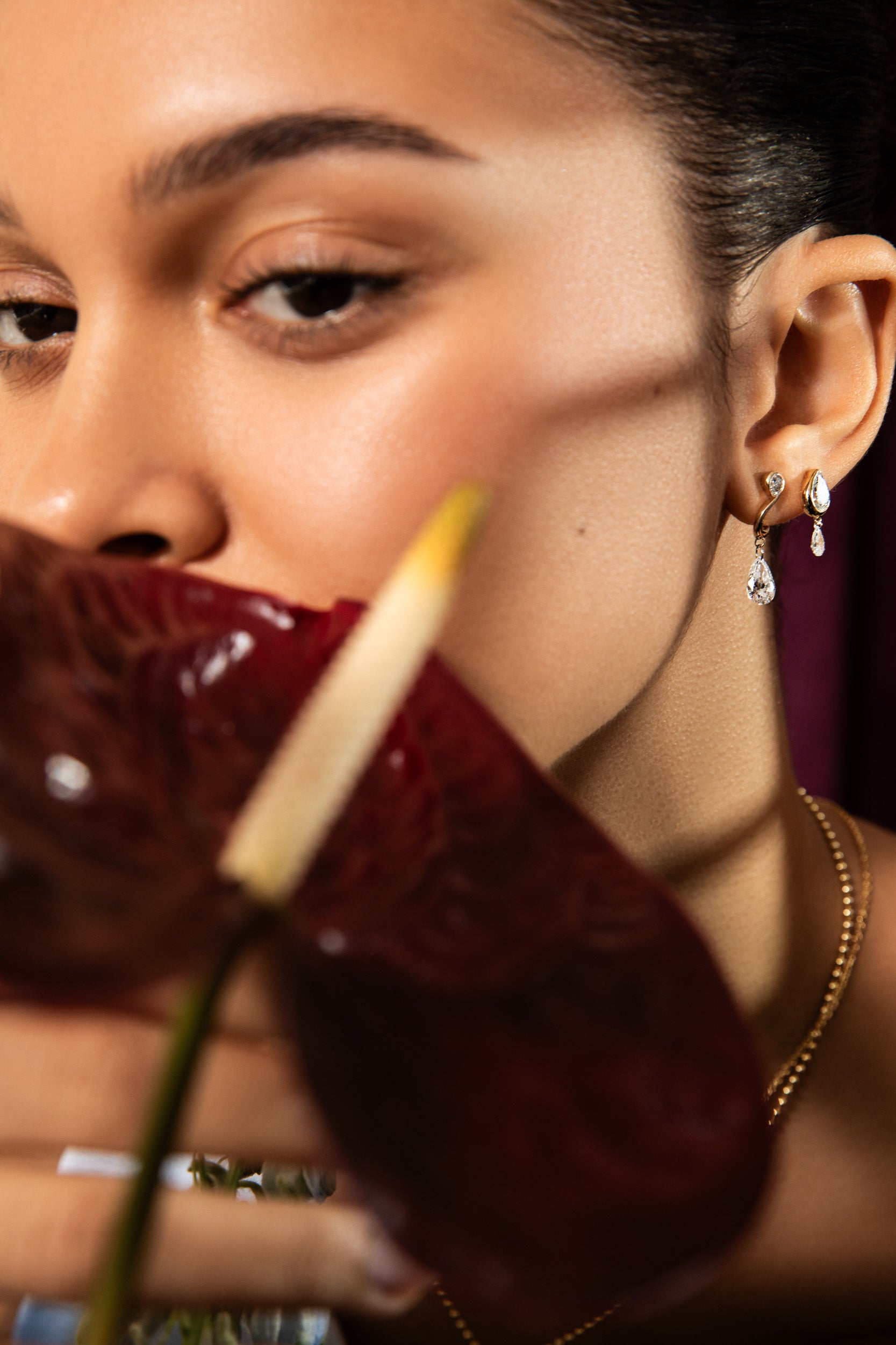 a model hides behind a red orchid modeling products from sophie ratner fine jewelry gift guide. This collection highlights the "treat yourself" collection of designs worth $1,500 and over. shop the collection.