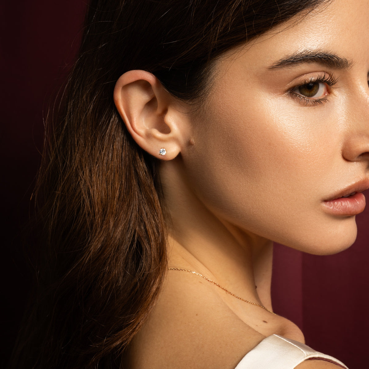 A person wearing a small round diamond stud earring.