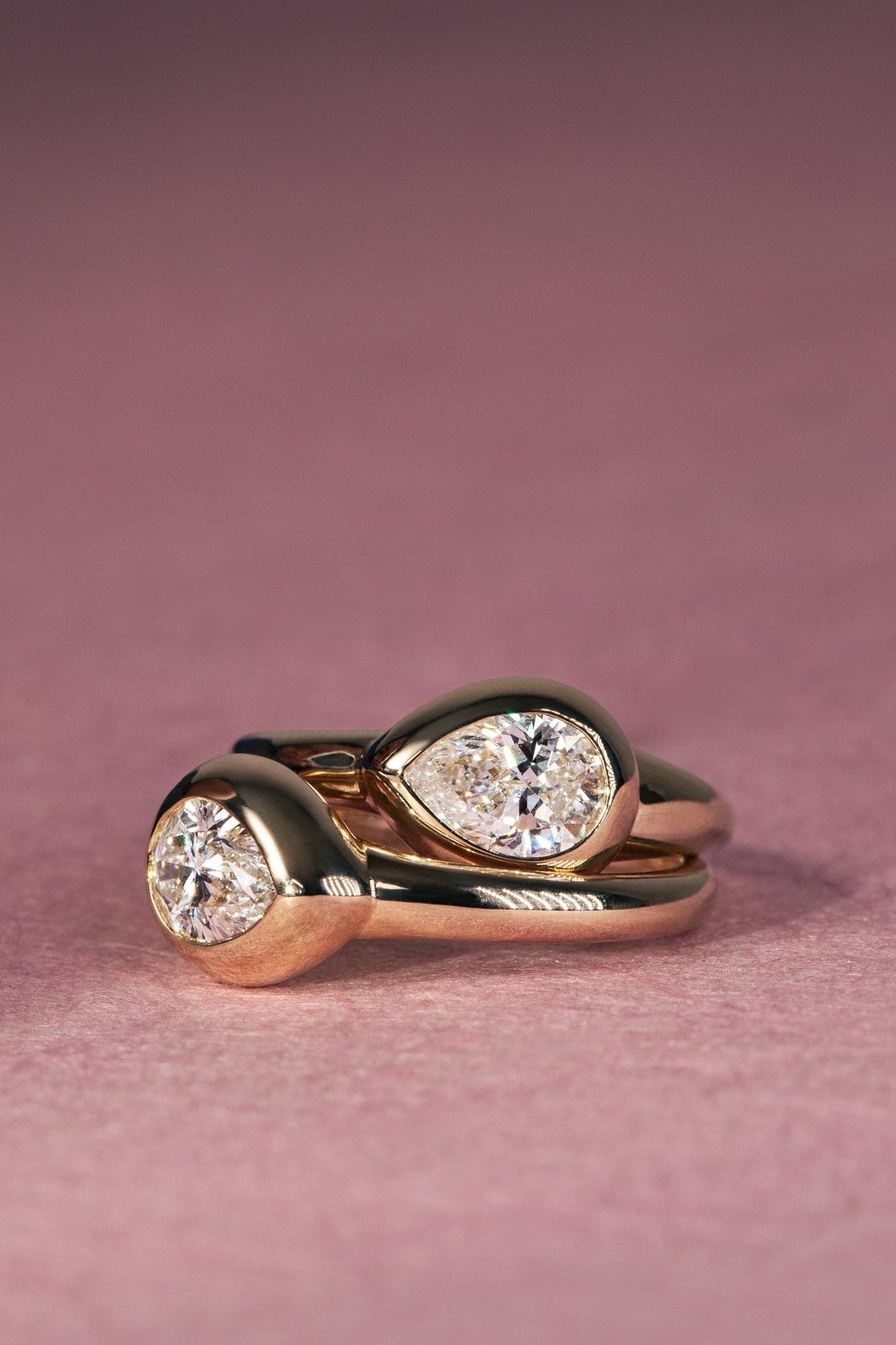 Rose gold ring with two diamond stones on a pink background