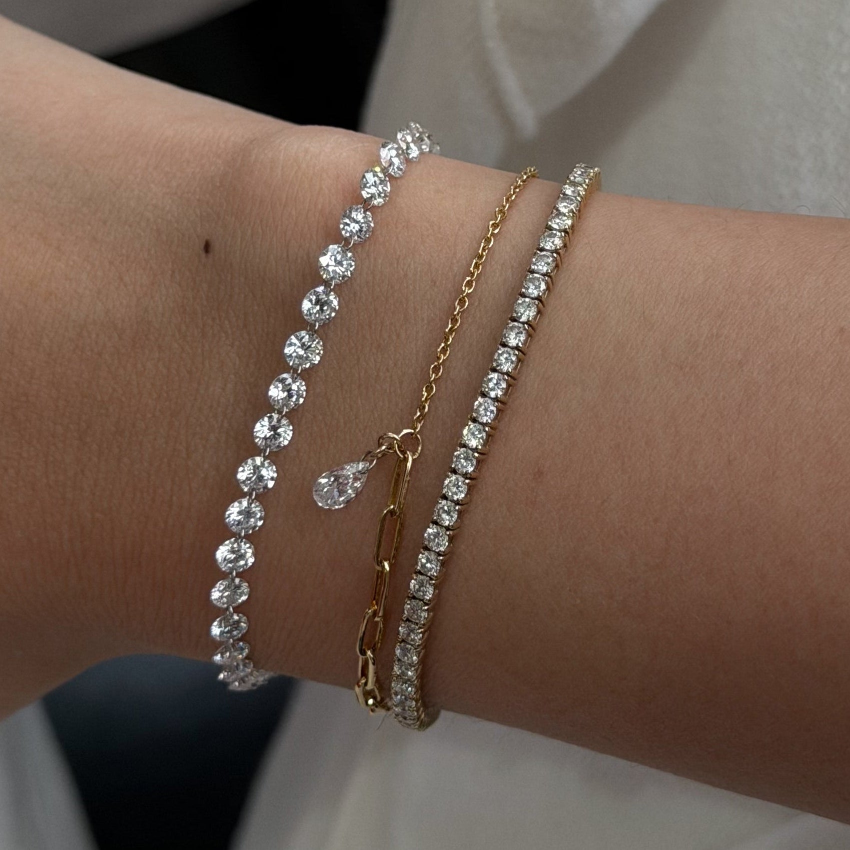 Close-up of a wrist wearing multiple bracelets on a plain background