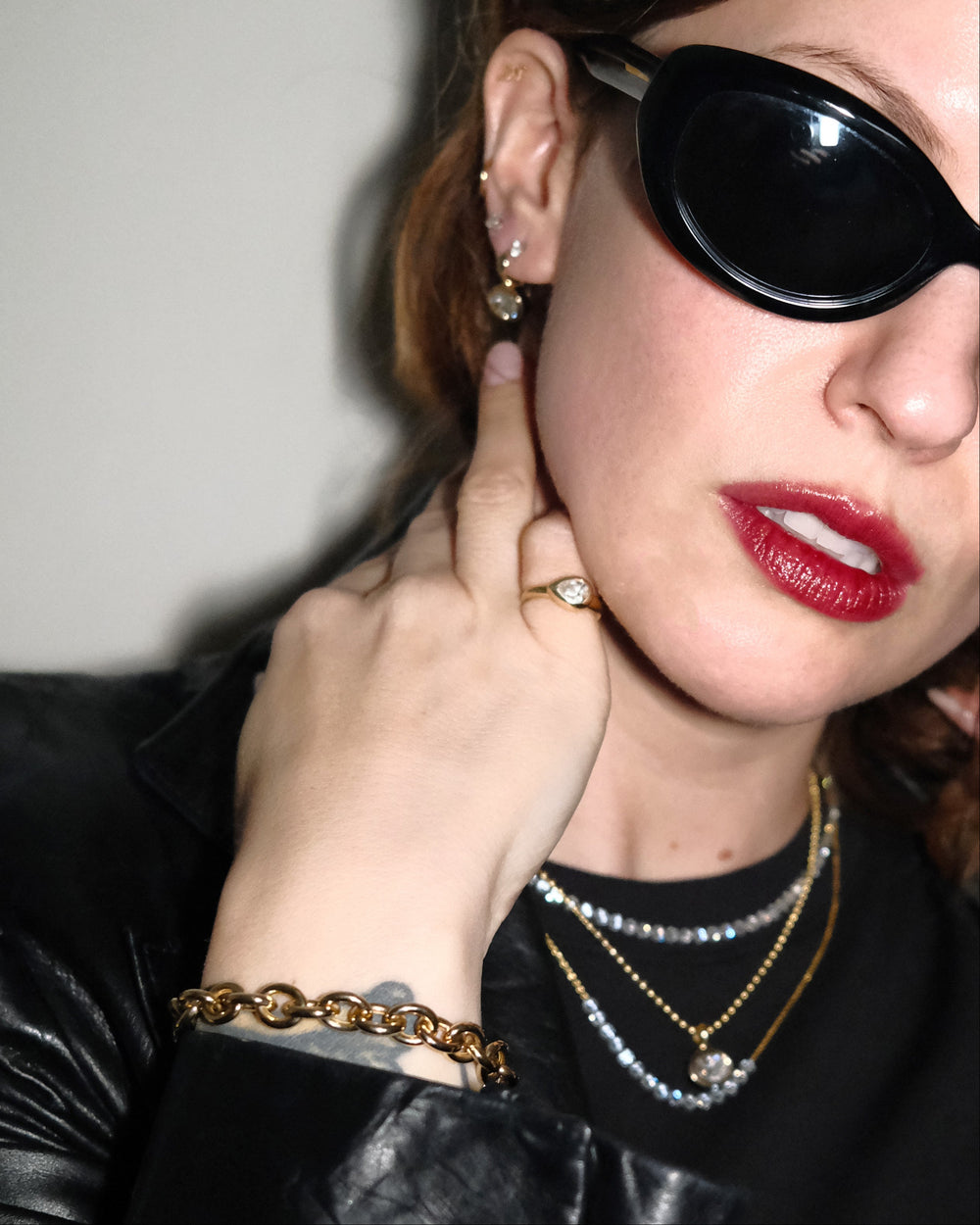 Woman wearing black sunglasses, a black leather jacket, and red lipstick.