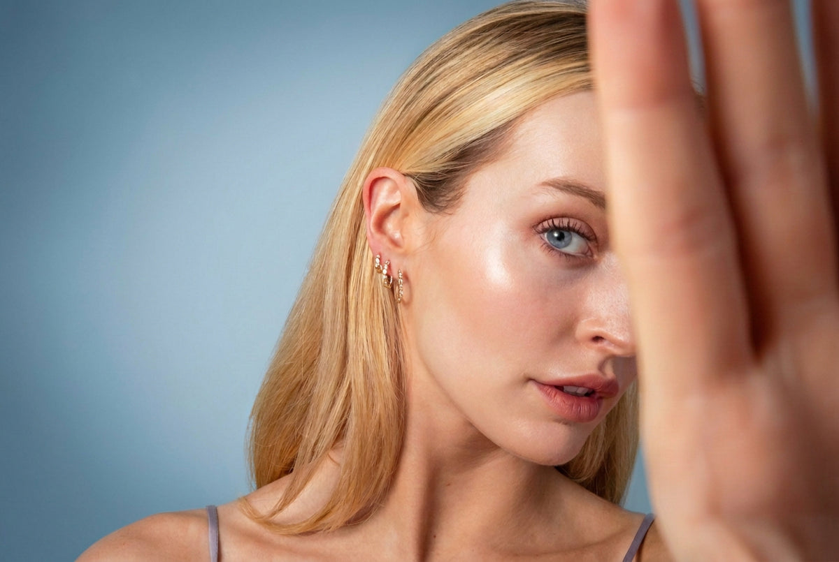 a model half covering the camera, models three diamond bezel hoops. promoting new customers to sign up to shop sophie ratner's holiday gift with purchase starting october 21st.
