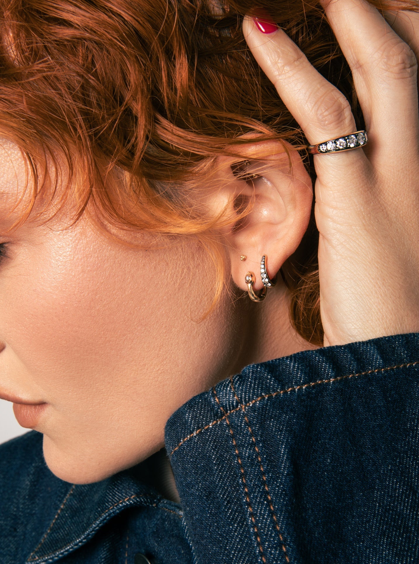 Emma Fineman modeling the thick gold tapered band and thick patina diamond band, wearing a denim jacket.