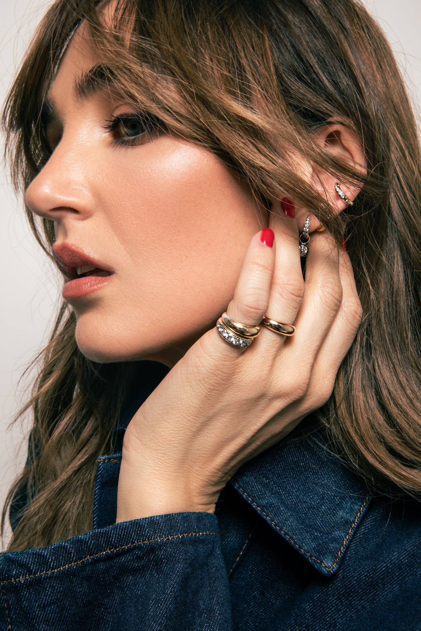 Chloe FIneman modeling the thick gold tapered band and thick patina diamond band, wearing a denim jacket.
