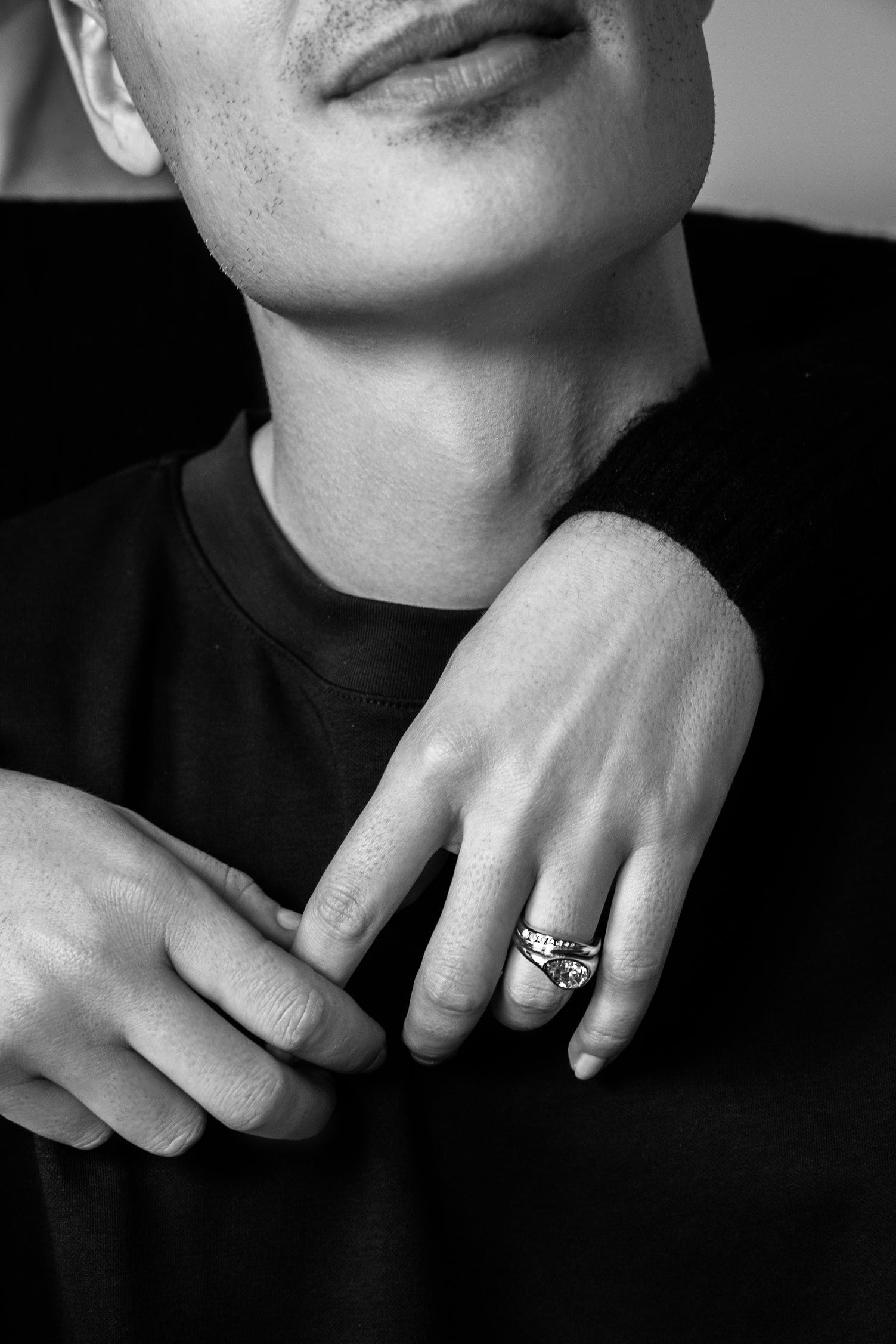 Black and white close-up of a person wearing a ring on their finger.