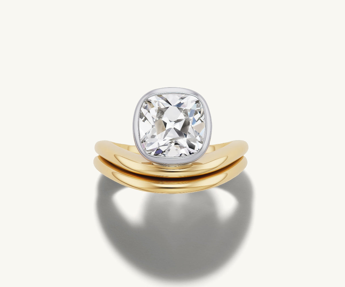 A custom old mine diamond engagement ring in platinum bezel on a 14k yellow gold waving band paired with a gold wedding band.