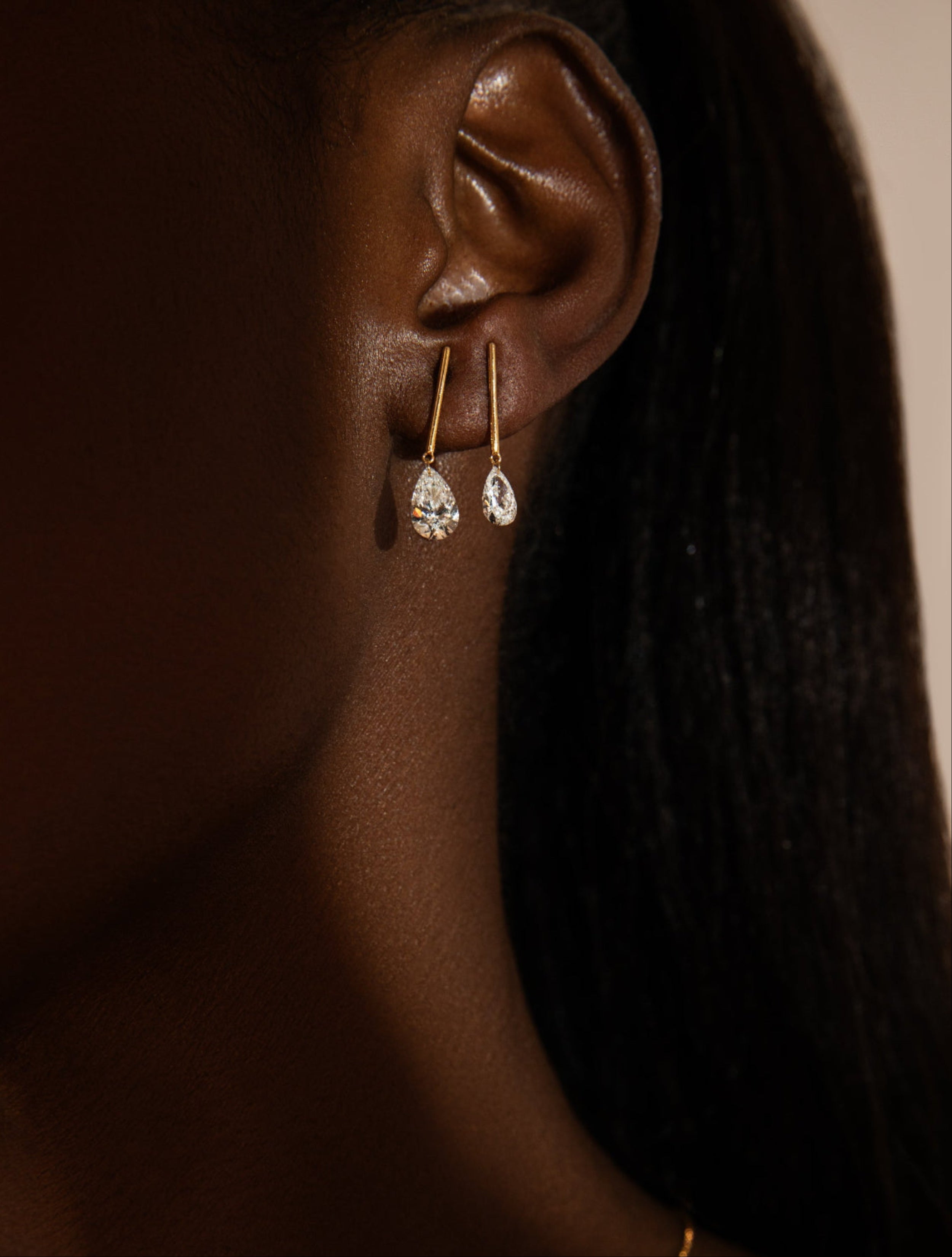 Close-up of a person wearing gold earrings with a blurred background