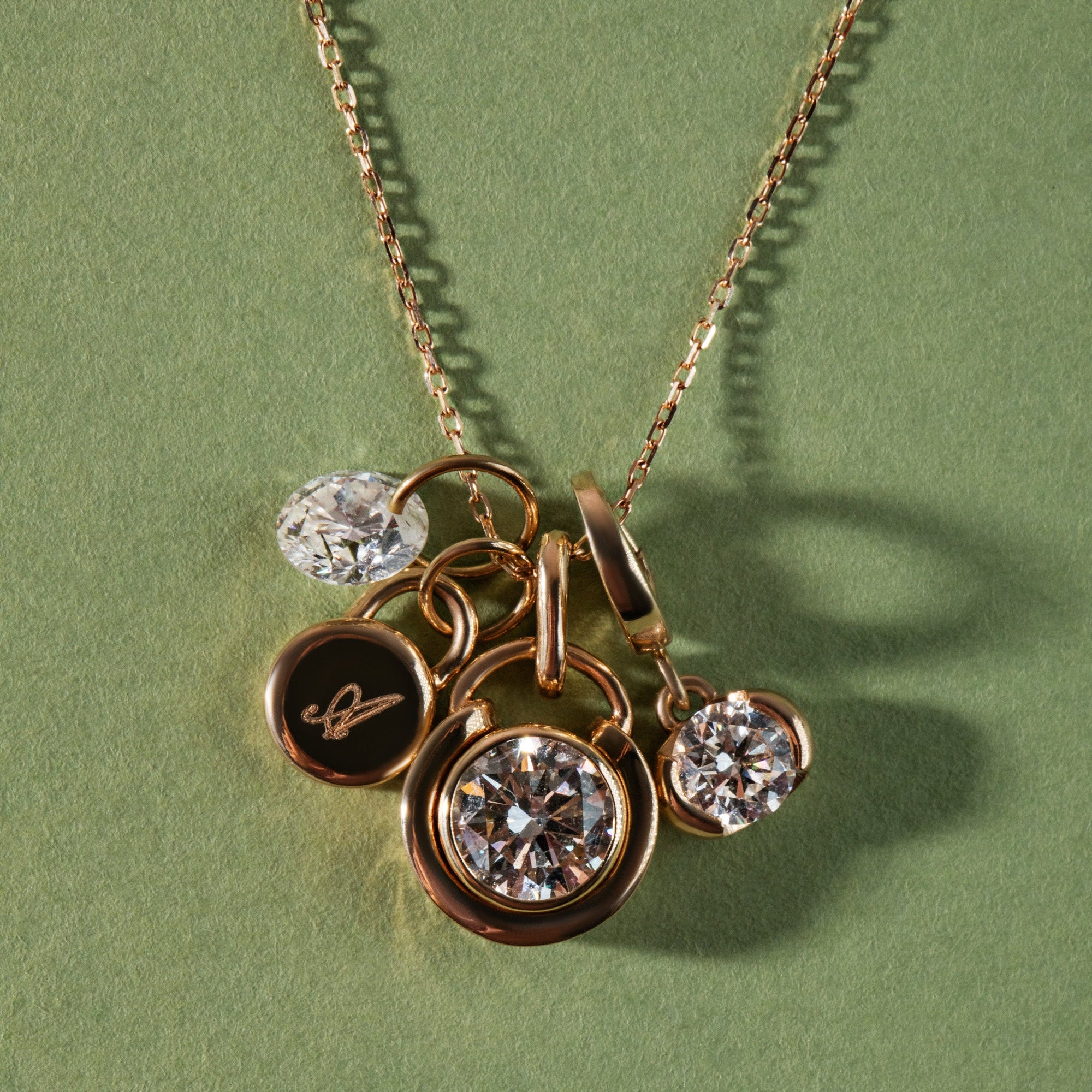 Gold necklace with three round pendants on a green background