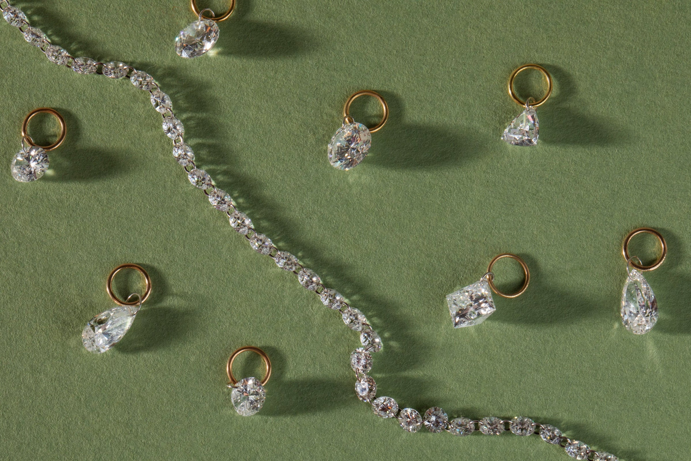 pierced diamond jewelry is scattered on a green background. shop in stock and ready to ship items by 05/07 for on time gifting by mother's day.