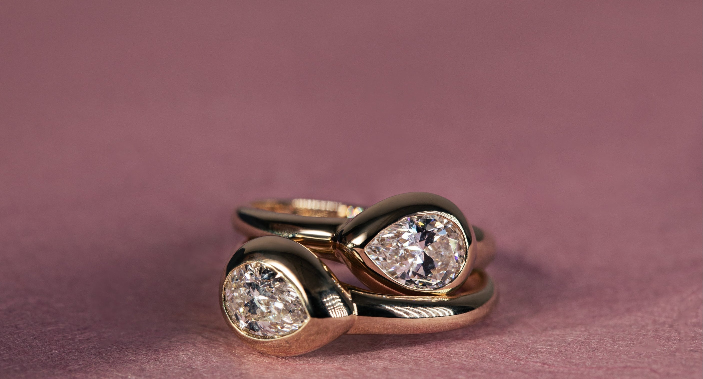 Pair of pear venus diamond pinky rings are staocked on a pink background to showcase the in stock and ready to ship collection for valentine's day. Shop in stock by 02/11 for delivery by 02/14
