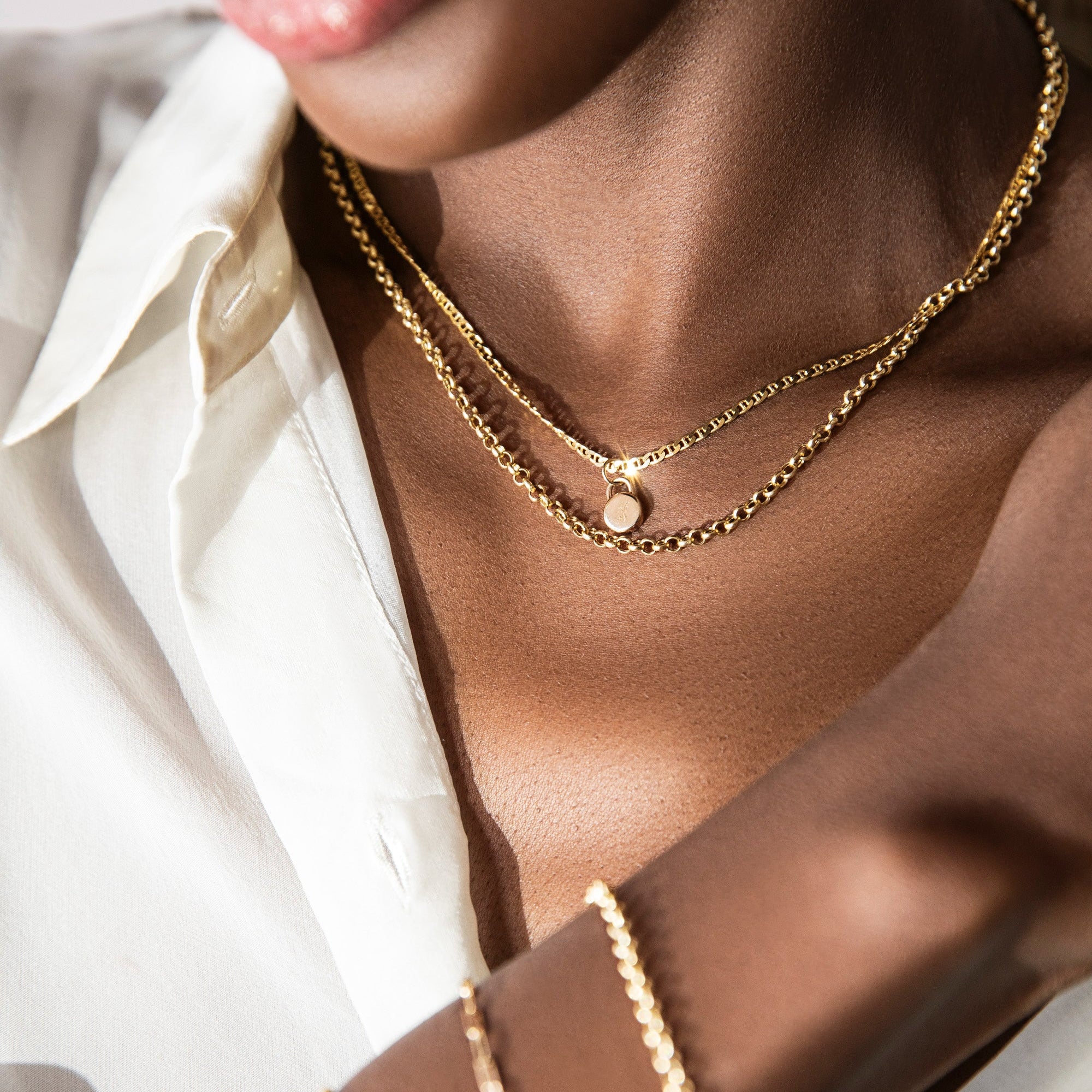 close up of a model wearing the free mini 14k gold love lock we're gifting with orders $800+ automatically added to applicable orders. shop now, while supplies last.