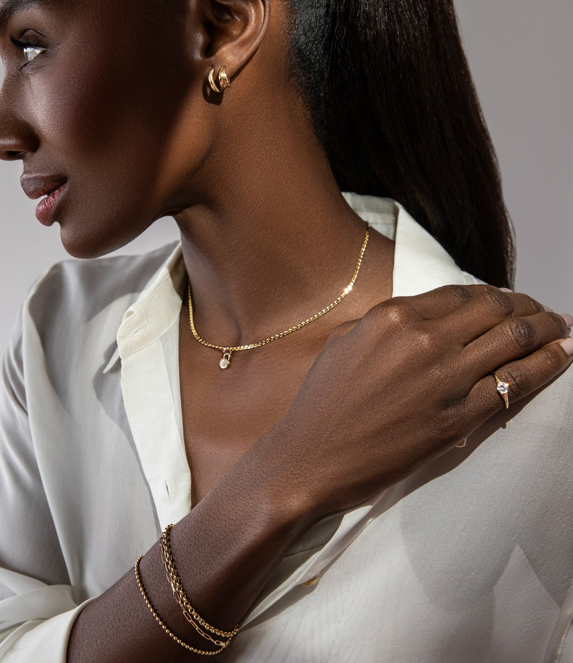 A model wears solid 14k gold sophie ratner fine jewelry. This image promotes our free lock with purchase on orders $800+. A solid 14k gold lock with a complimentary engraving, shop now. 