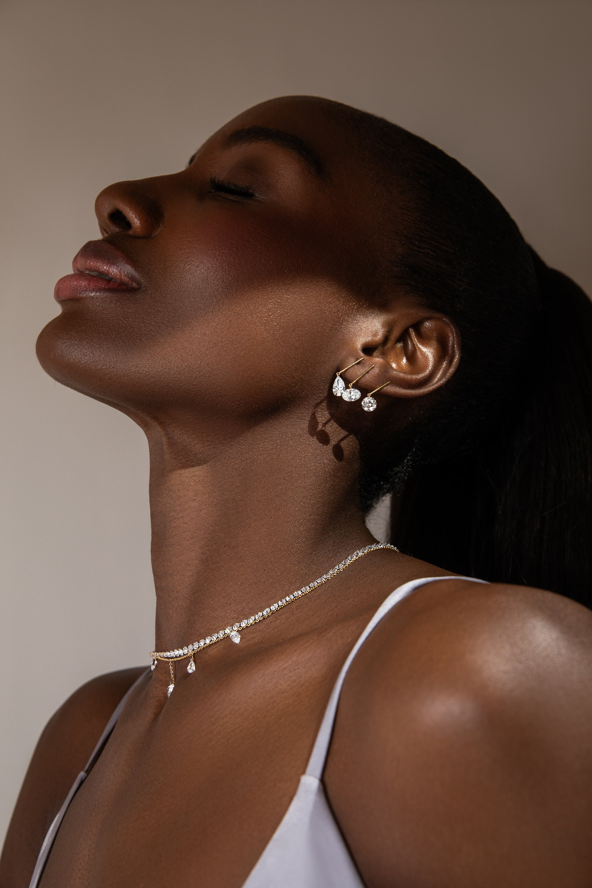model awa wearing three pierced diamond and gold bar earrings with the 1 carat pear, round and oval lab grown diamonds. shop the latest pierced diamond collection
