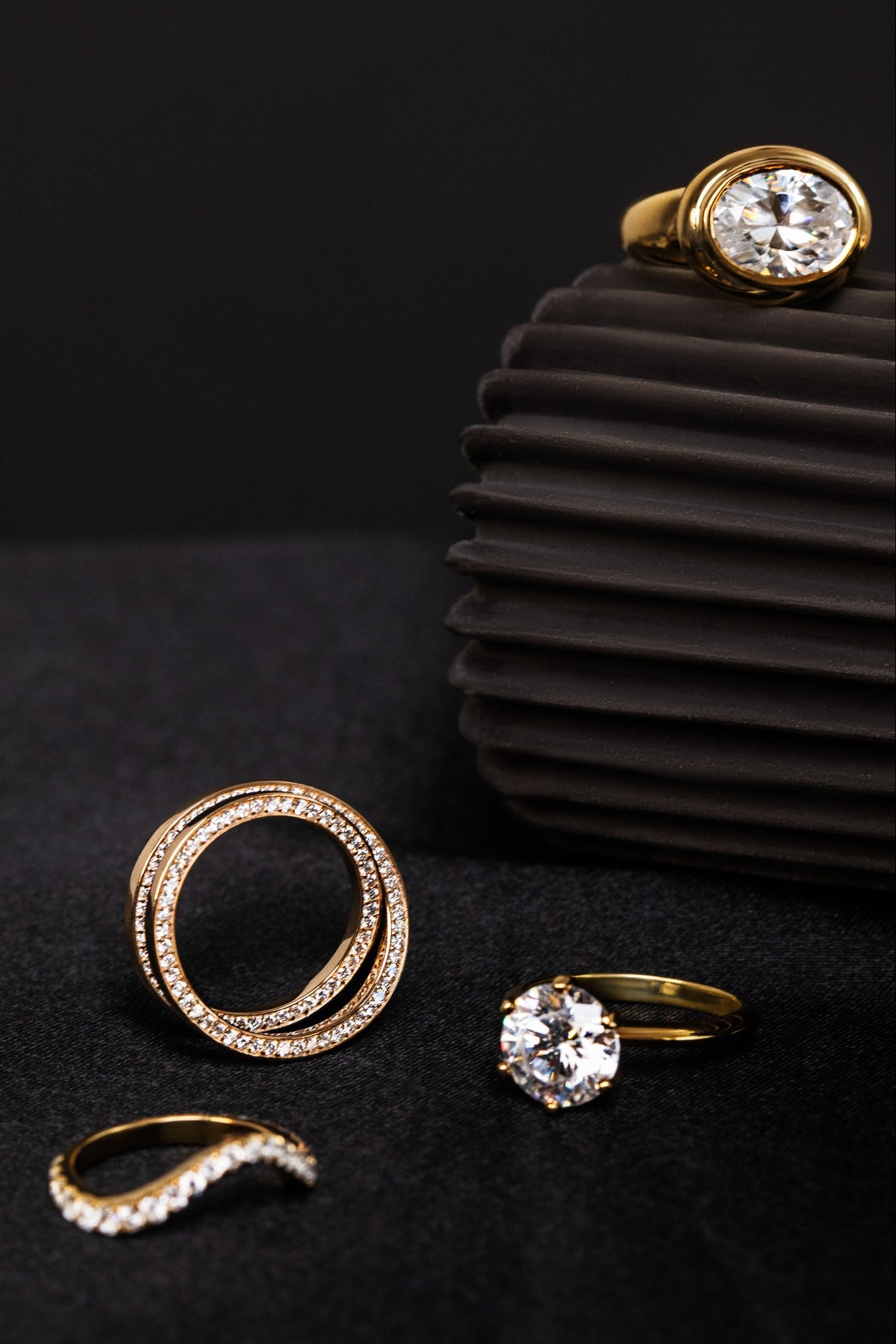 Gold rings with diamonds on a black background showcasing one of a kind custom designs by Sophie ratner. learn more about custom bridal and engagement.