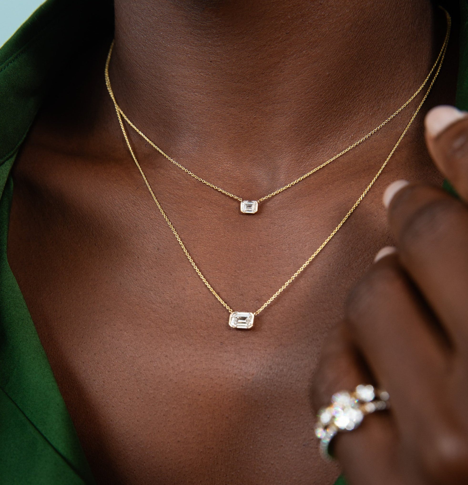 model wearing a open green button down shirt modeling the new emerald sunrise pendants in a medium and large size. shop the new sophie ratner fall collection,