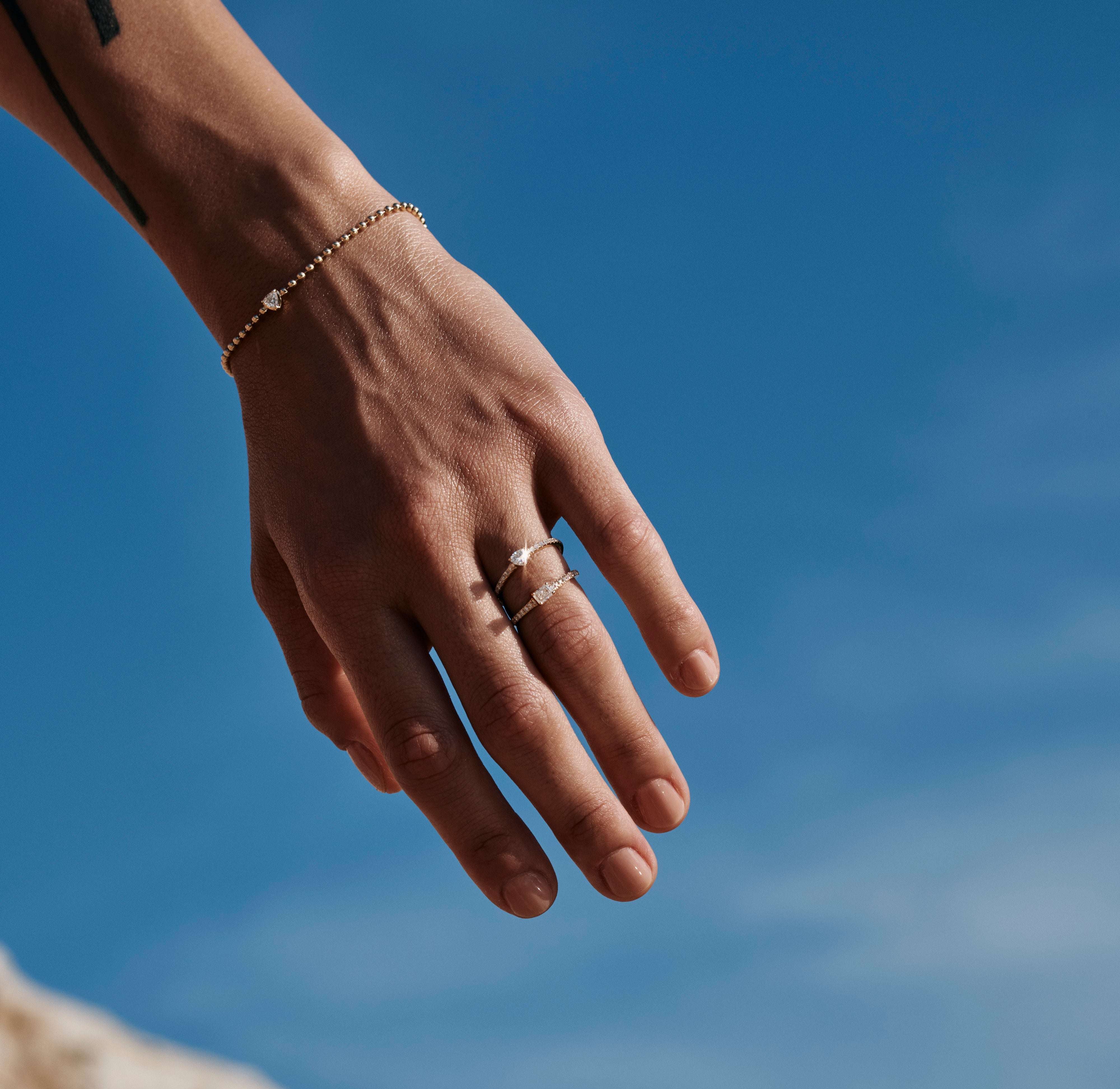 Hand with a ring and bracelet against a blue sky. shop our subsriber only vault sale up to 20% off. 